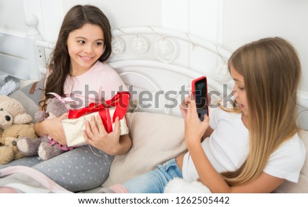 Sending video and pics. Happy small children with mobile phone. Small girls use phone in bed. Taking Christmas and New Year photo with smartphone. Merry Christmas and Happy New Year greetings.