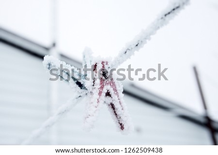 frozen icy snow-covered clothespins outside in winter, low temperatures