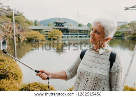 
Middle-aged occidental woman discovering the nipon country. Tourism in the temples and gardens of Kyoto in Japan taking pictures with her phone. Travel photography