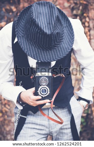 Unrecognizable fedora man photographing with vintage medium format photo camera. 