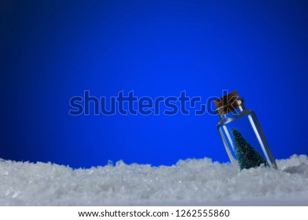 Frozen Christmas Tree in bottle on blue snowy background with copy space. Christmas and New Year background.