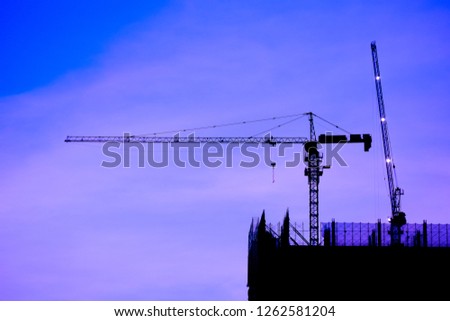 Crane and building construction site at sunset. High-quality stock photo image silhouette of construction tower crane group with sunset sky background. Building construction with crane during sunset