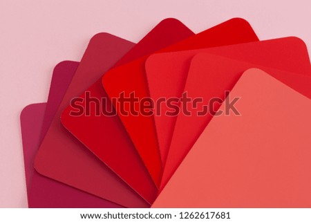 Paint color catalogue sample cards spread in fan shape - hues of red with copy space