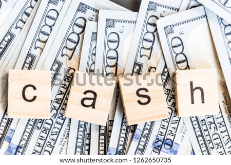 Word cash lying on one hundred dollars bill