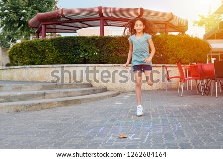 Girl playing hopscotch game on the asphalt on playground.