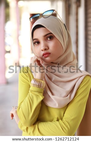 Portrait of cute Asian girl wearing hijab in yellow blouse. Sweet heart girl. Minimal make up look.