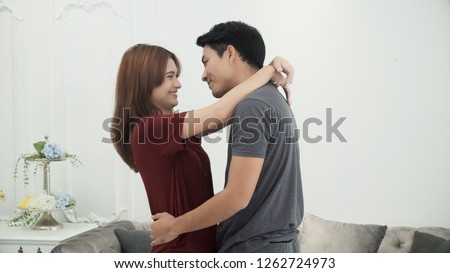 The happy attractive couple dancing at home, beautiful woman hold her hand on neck of her boyfriend, handsome man hug her in his arms and turn around in step dance with happiness together.