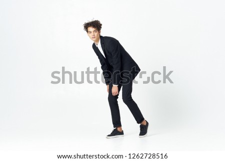 Curly guy in a trousers shirt and jacket goes on an isolated white background                   