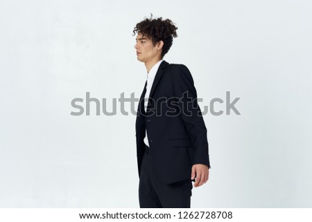 Young curly man in a jacket and trousers on a gray background business finance                 