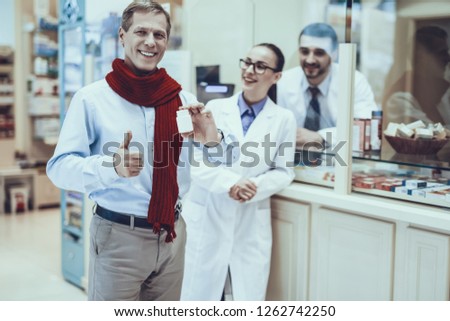 Happy Healthy Man Holding Bottle with Pills. Pharmacists Standing at Counter. Man is Showing OK Sign. Pharmacists is Wearing Special Medical Uniform. People is Located in Pharmacy.
