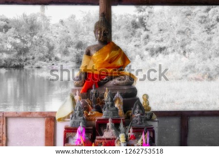 This unique picture shows a Buddha statue on a lake. The Budha has an orange cape.