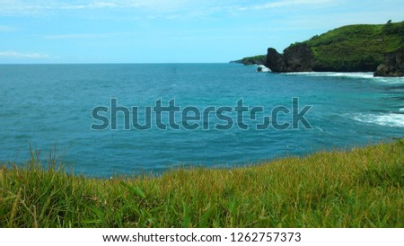 composition of natural background, bright green grass and blue sky, with ocean in the background. Widodaren beach, Gunungkidul, Yogyakarta, Indonesia