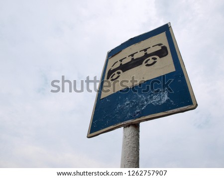 Old rusty bus stop sign against a blue sky       
