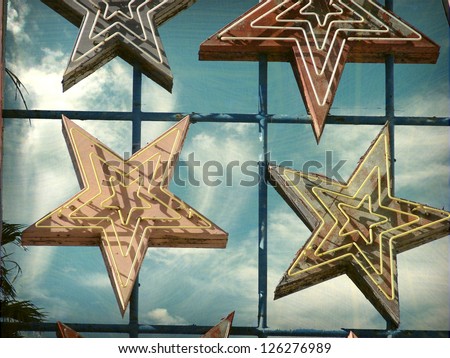   aged and worn vintage photo of neon sign stars
