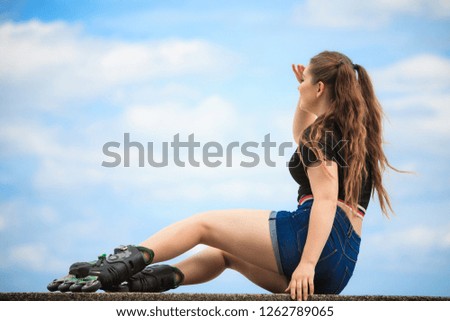 Happy joyful young woman wearing roller skates relaxing after long ride. Female being sporty having fun during summer time near sea.