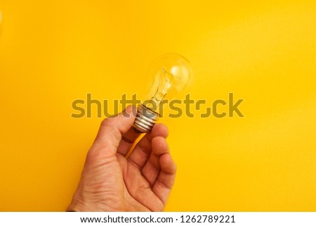 light bulb in his hand on a yellow background