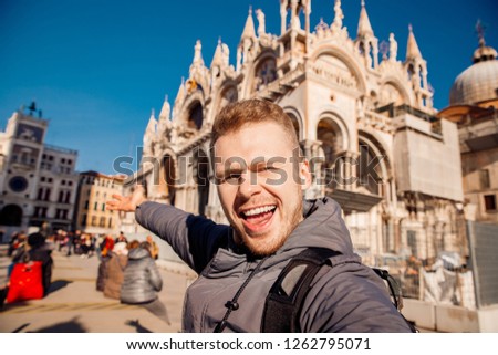 Tourist makes selfie photo on background Basilica di San Marco in Venice, Italy against bright blue sky.