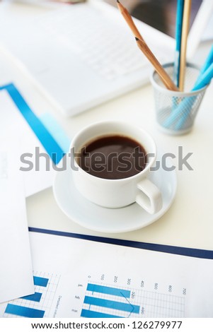 Vertical image of an office workplace with papers, stationary and a cup of coffee