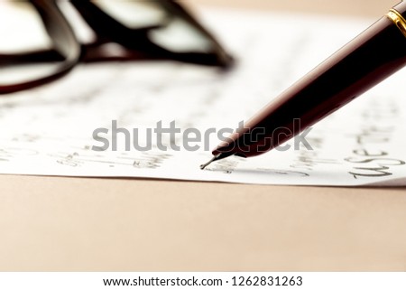 vintage fountain pen writing a letter, glasses behind