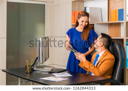 Elegant secretary bringing some documents for signature to her boss and working together in the office. Copy space