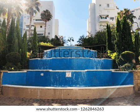 Residential buildings and fountain surrounded with green plants in  Rishon Le Zion.