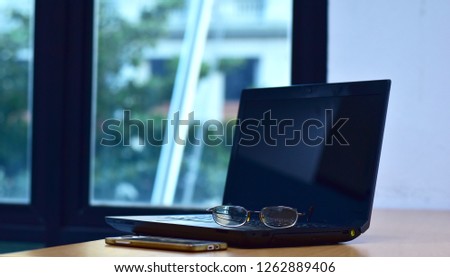 Glasses on laptop computer with smartphone on desk