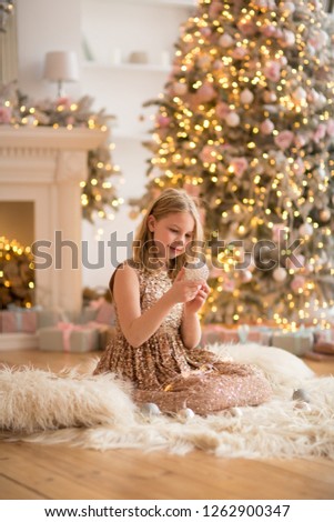 beautiful girl sitting on the floor near the Christmas tree in the new year interior