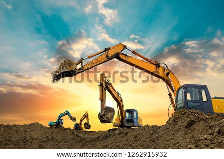 Four excavators work on construction site at sunset Royalty-Free Stock Photo #1262915932