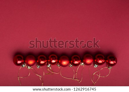 Red Christmas tree decorative toy balls on red celebratory Christmas background laid out in horizontal line. New Year's holidays. Christmas holidays.