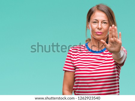 Middle age senior hispanic woman over isolated background doing stop sing with palm of the hand. Warning expression with negative and serious gesture on the face.