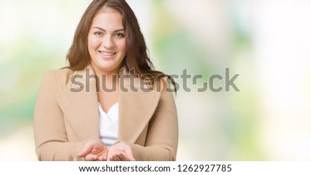 Beautiful plus size young woman wearing winter coat over isolated background Smiling with hands palms together receiving or giving gesture. Hold and protection