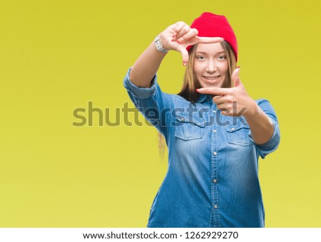 Young caucasian beautiful woman wearing wool cap over isolated background smiling making frame with hands and fingers with happy face. Creativity and photography concept.