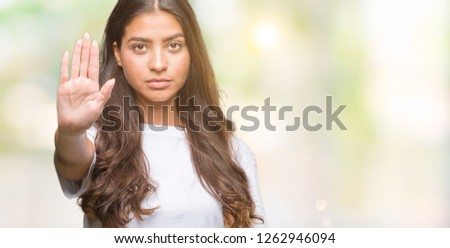 Young beautiful arab woman over isolated background doing stop sing with palm of the hand. Warning expression with negative and serious gesture on the face.