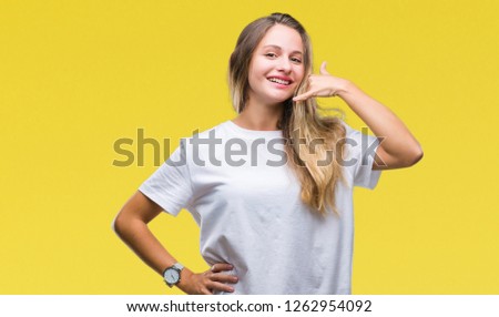 Young beautiful blonde woman wearing casual white t-shirt over isolated background smiling doing phone gesture with hand and fingers like talking on the telephone. Communicating concepts.