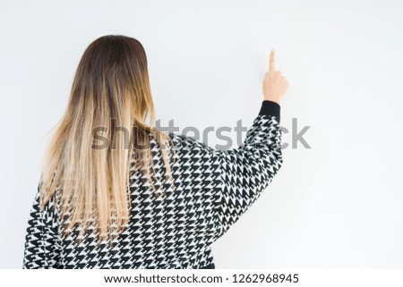 Young woman wearing casual sweater over isolated background Posing backwards pointing behind with finger hand