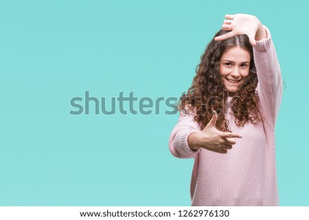 Beautiful brunette curly hair young girl wearing pink winter sweater over isolated background smiling making frame with hands and fingers with happy face. Creativity and photography concept.