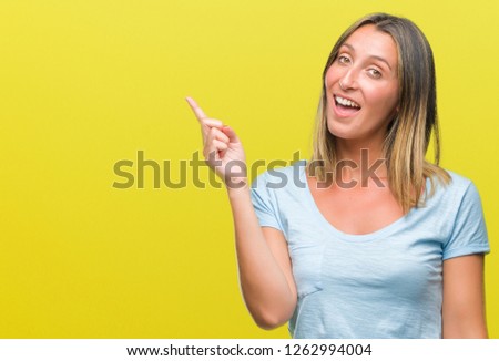 Young beautiful woman over isolated background with a big smile on face, pointing with hand and finger to the side looking at the camera.