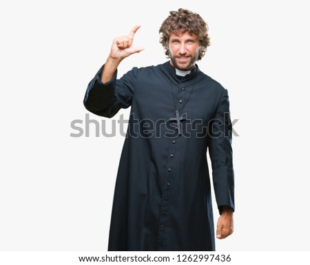 Handsome hispanic catholic priest man over isolated background smiling and confident gesturing with hand doing size sign with fingers while looking and the camera. Measure concept.