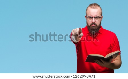 Young hipster man wearing glasses and reading a book over isolated background pointing with finger to the camera and to you, hand sign, positive and confident gesture from the front