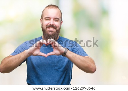 Young caucasian hipster man over isolated background smiling in love showing heart symbol and shape with hands. Romantic concept.