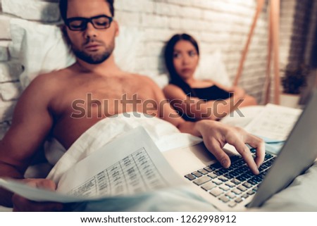 Young Couple in Bed, Man Working Laptop Bored Wife. Businessman Working on Computer in Bed while Wife Unhappy. Working home Concept. Business Concept. Working Overtime. Relationship Problem.