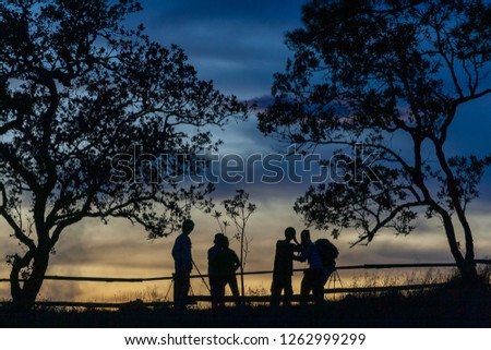 Silhouette picture of group of tourist with twilight sunset background. Backpackers and photographer with tree and colorful winter sky on high mountain .Phu soi dao national park , Uttaradit, Thailand