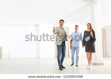 Real estate agent showing new apartment to young couple. Space for text Royalty-Free Stock Photo #1263001408
