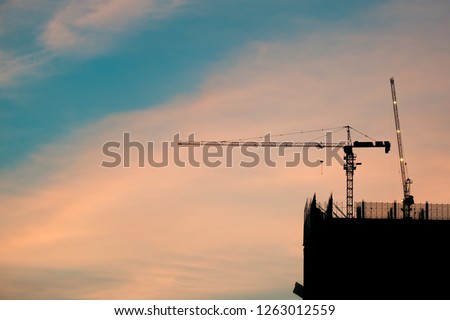 Crane and building construction site at sunrise. High-quality stock photo image silhouette of construction tower crane with sunrise sky background. Building construction with crane during sunrise