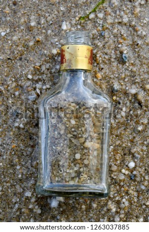 Old dirty glass bottle on a sandy beach