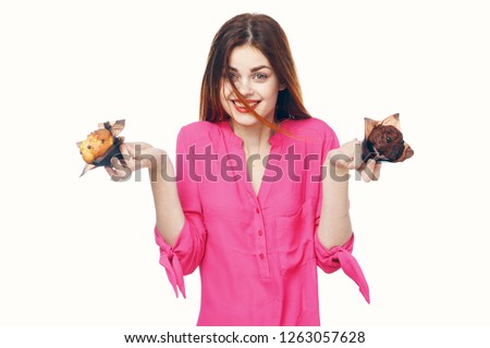 Joyful pretty woman in a pink blouse holding cupcakes in her hands                   