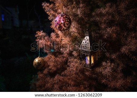Bauble on tree. Christmas and New Year decoration on the pine tree branch with lights at the background at night outdoors. Concept of winter holidays. Selective focus