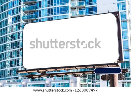 Blank advertising billboard in front of modern buildings with blue glass facade