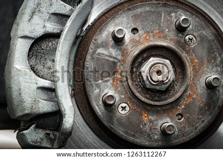 Close-up of the replacement of the old front brake disc, brake caliper and hub nut on a car lifted on a lift with the help of a pneumatic wrench in a car repair shop. Auto mechanic repair.