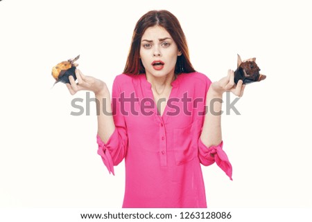 Surprised woman in a pink shirt and with bright makeup holds two cupcakes in her hands                  